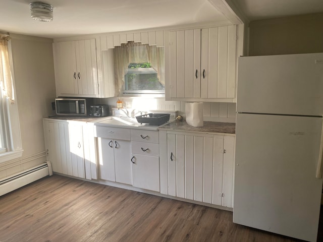 kitchen with wood-type flooring, white fridge, sink, wall chimney exhaust hood, and white cabinets