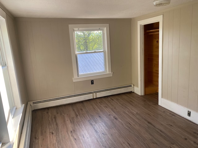 unfurnished room featuring a textured ceiling, dark hardwood / wood-style floors, and a baseboard heating unit