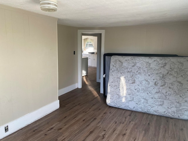 unfurnished bedroom with a textured ceiling and dark wood-type flooring