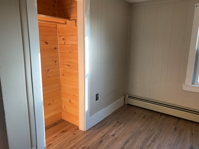 empty room with light hardwood / wood-style floors and a baseboard heating unit