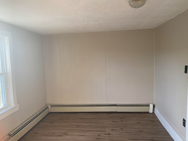 spare room with a textured ceiling, dark hardwood / wood-style floors, and a baseboard heating unit