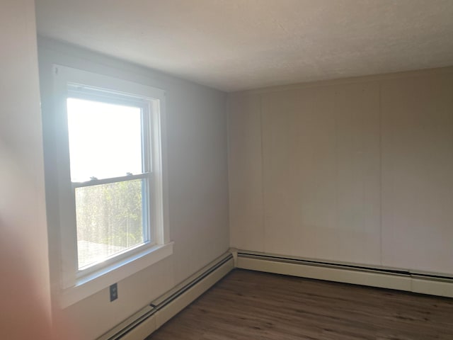 empty room featuring a baseboard heating unit and dark hardwood / wood-style flooring