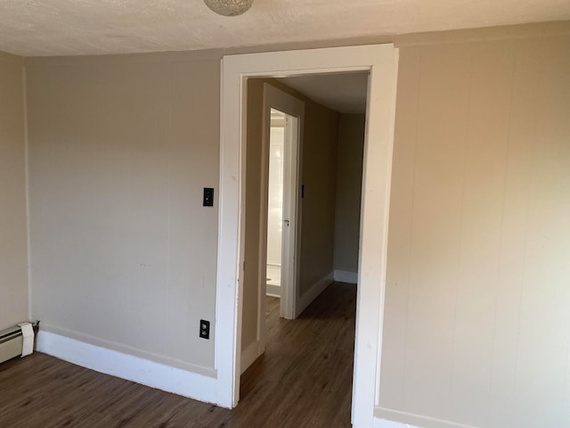 hall with a textured ceiling, dark hardwood / wood-style floors, and baseboard heating