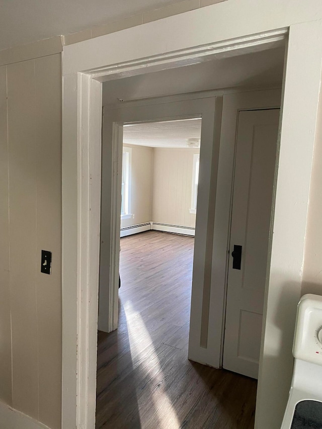 hallway with a baseboard radiator, dark wood-type flooring, and washer / clothes dryer