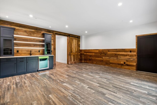 kitchen featuring rustic walls, wine cooler, light hardwood / wood-style floors, a barn door, and wood walls