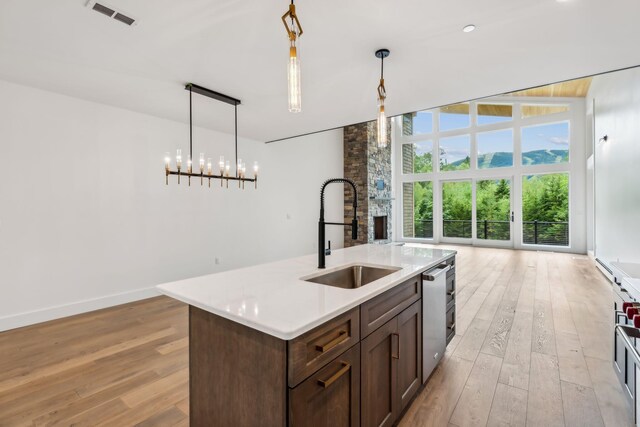 kitchen featuring sink, decorative light fixtures, light hardwood / wood-style flooring, dishwasher, and a kitchen island with sink