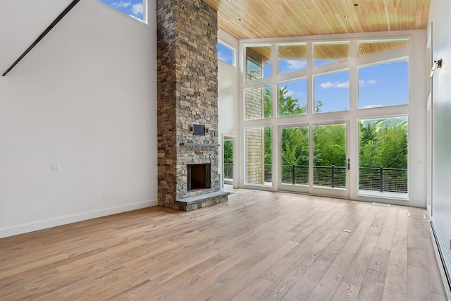 unfurnished living room with light hardwood / wood-style flooring, a fireplace, wooden ceiling, and a high ceiling