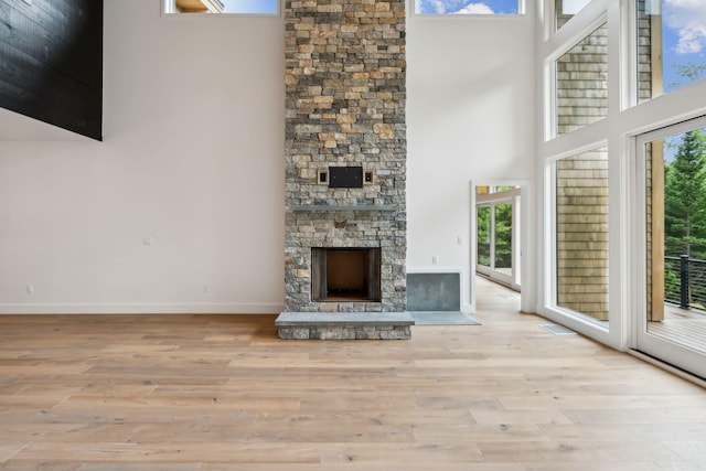 unfurnished living room with light wood-type flooring, plenty of natural light, and a high ceiling