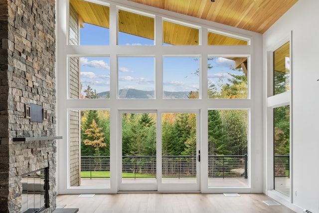 doorway to outside with a fireplace, plenty of natural light, high vaulted ceiling, and wood ceiling