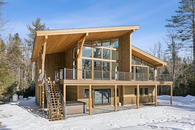 snow covered rear of property with a deck