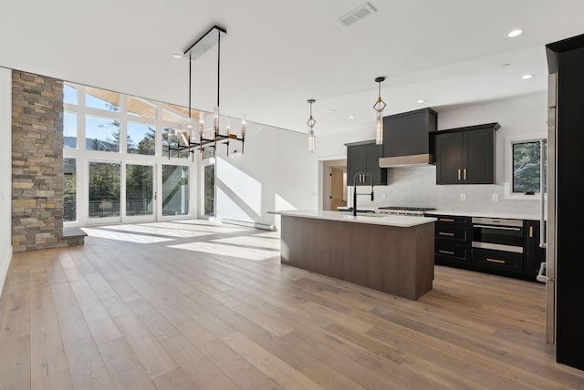 kitchen with a healthy amount of sunlight, sink, pendant lighting, and a kitchen island with sink