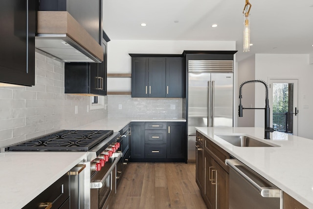 kitchen with premium range hood, sink, tasteful backsplash, decorative light fixtures, and stainless steel appliances