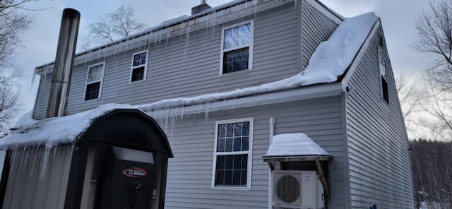 snow covered rear of property with ac unit