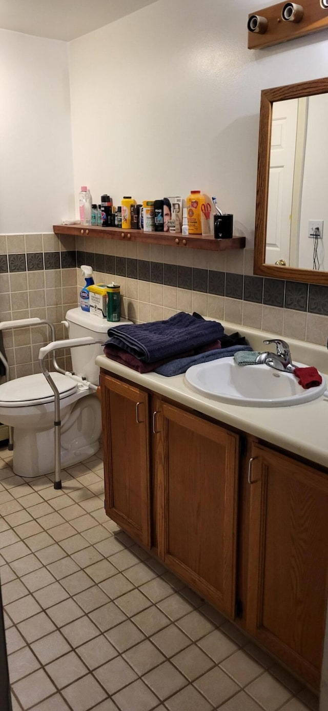 bathroom with toilet, tile walls, tile patterned flooring, and vanity