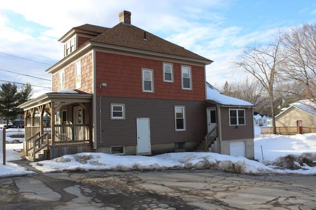 snow covered rear of property with a porch