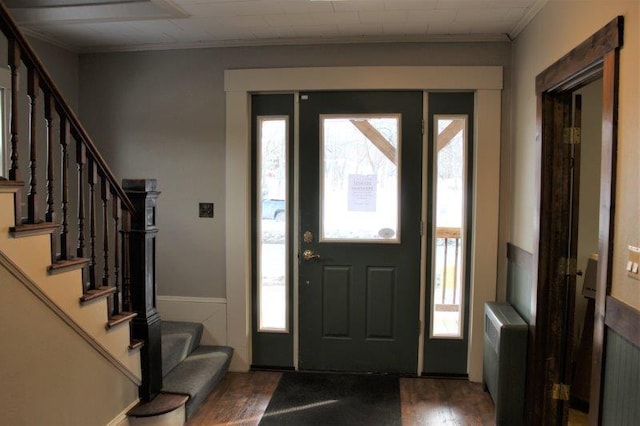 foyer entrance with ornamental molding and dark wood-type flooring