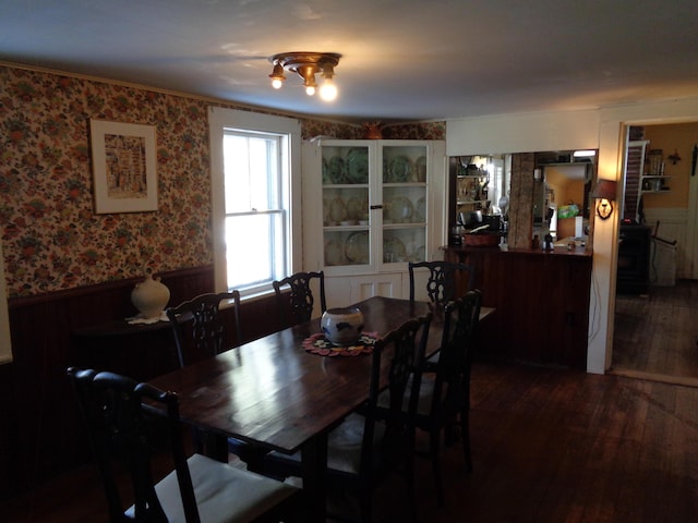 dining area with wallpapered walls, wood finished floors, and a wainscoted wall