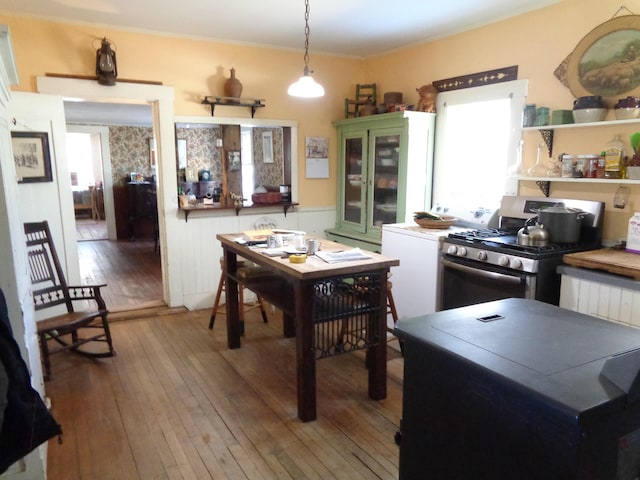 kitchen featuring gas range, hardwood / wood-style flooring, crown molding, and a wealth of natural light