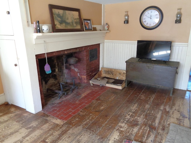 living room featuring wainscoting, a fireplace, and hardwood / wood-style flooring