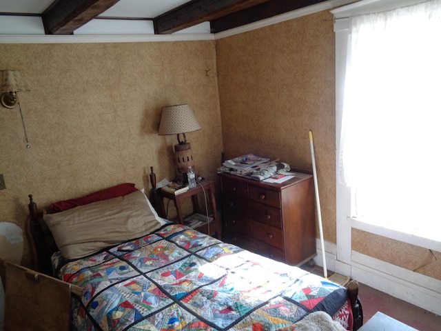 bedroom with beam ceiling and wallpapered walls