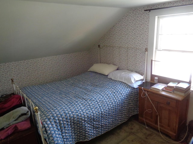 bedroom with wallpapered walls and lofted ceiling