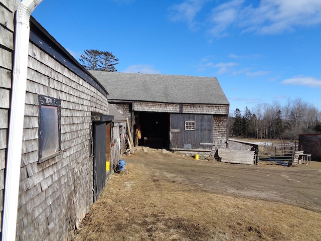 view of home's exterior with an outdoor structure and a shingled roof