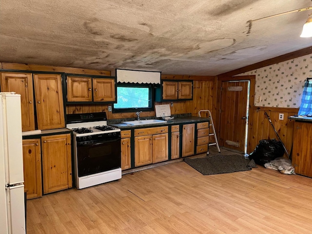 kitchen featuring a textured ceiling, light wood-type flooring, and white appliances