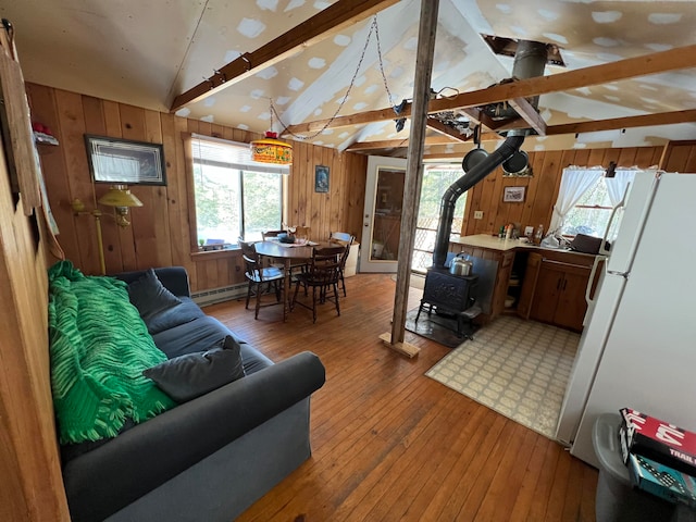 living room featuring vaulted ceiling with beams, a wood stove, and plenty of natural light