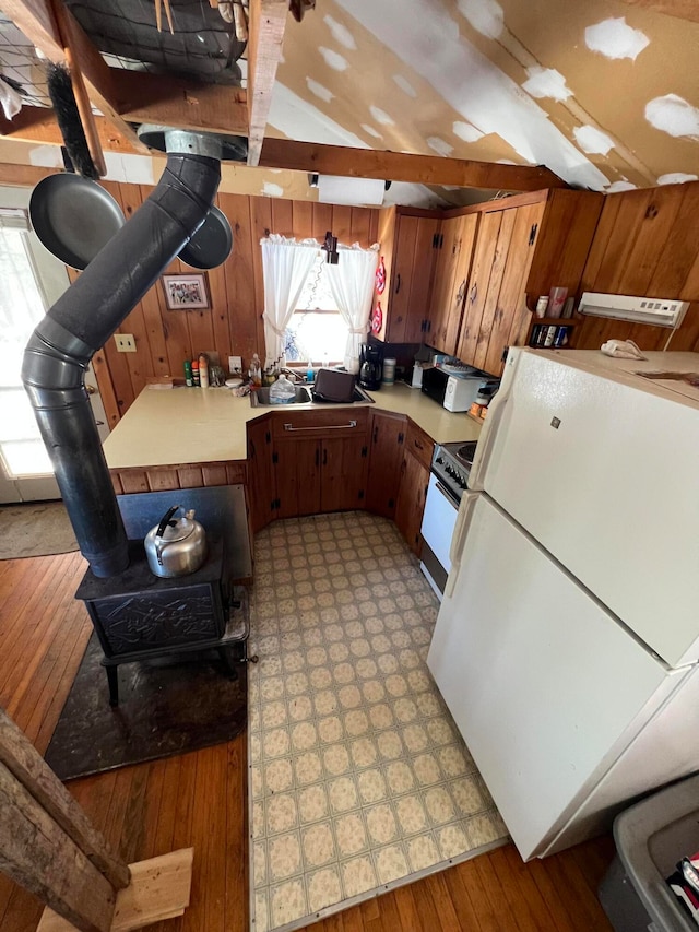 kitchen with light hardwood / wood-style flooring, wood walls, lofted ceiling with beams, and white appliances