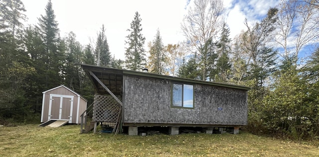 rear view of property featuring a storage unit and a yard