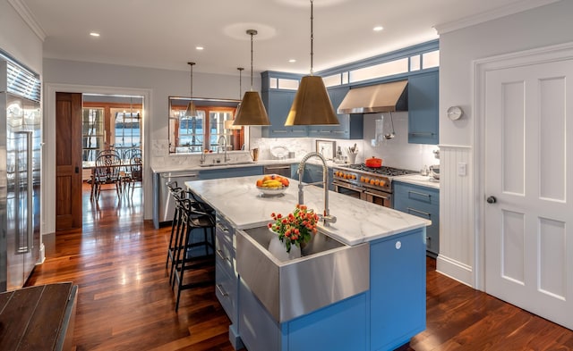 29 Summerhaven Ln, Boothbay, ME 04544 - kitchen featuring exhaust hood, blue cabinetry, stainless steel appliances, a kitchen bar, and dark wood-style flooring