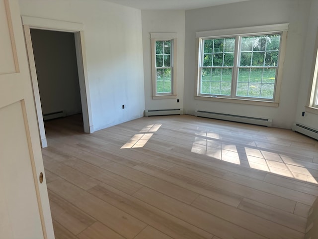 empty room featuring baseboard heating and light wood-type flooring