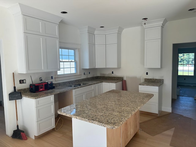 kitchen with light hardwood / wood-style floors, white cabinets, and a center island