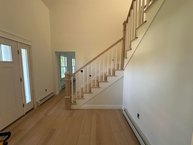 entrance foyer with light hardwood / wood-style floors, a high ceiling, and a baseboard radiator