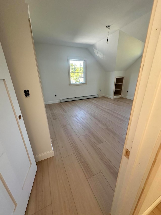 additional living space featuring baseboard heating, lofted ceiling, and light hardwood / wood-style flooring