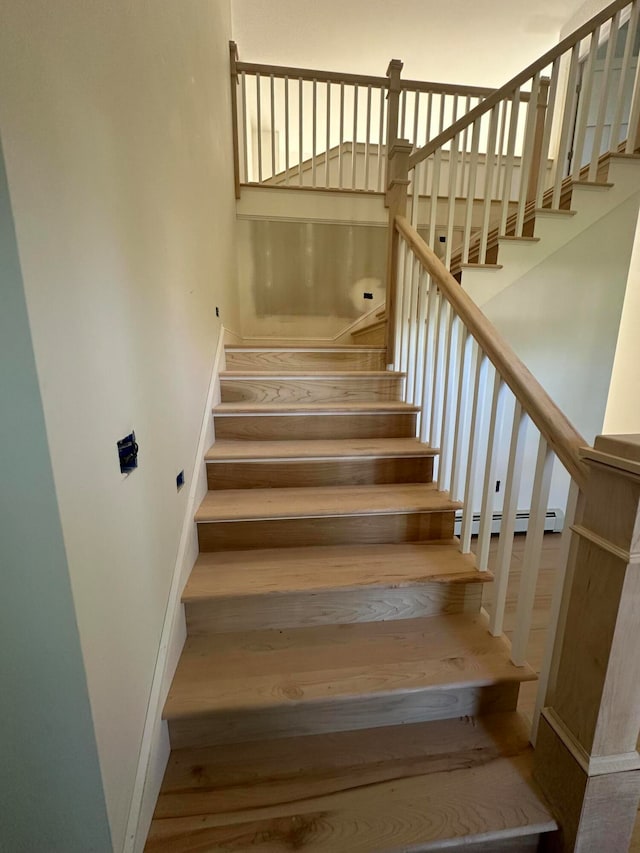 staircase with wood-type flooring and baseboard heating