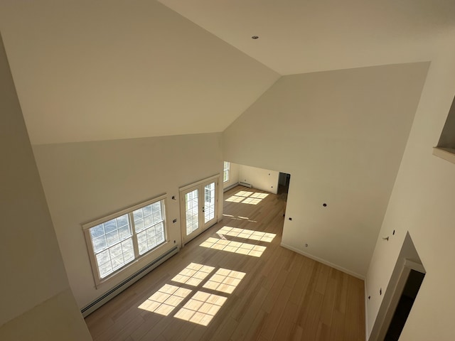 additional living space featuring french doors, light wood-type flooring, high vaulted ceiling, and baseboard heating