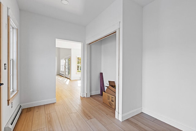 hallway with a baseboard heating unit and light hardwood / wood-style flooring