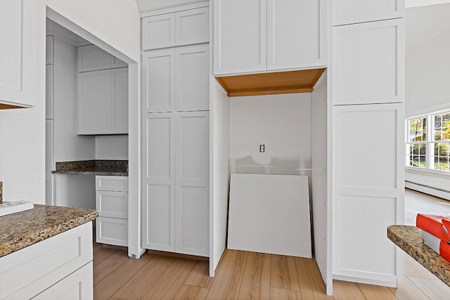 kitchen featuring a baseboard radiator, light hardwood / wood-style flooring, white cabinets, and dark stone counters