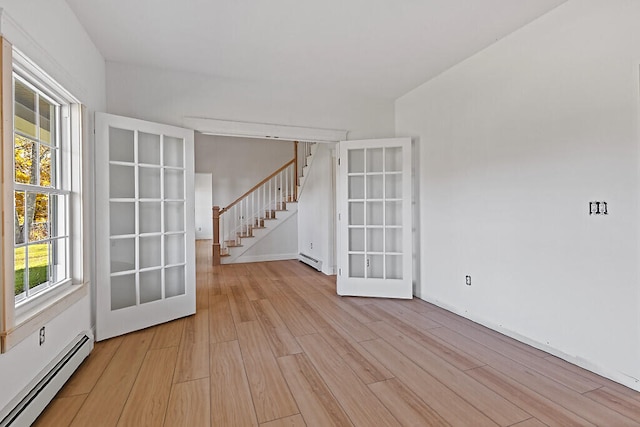 empty room with french doors, a baseboard heating unit, and light wood-type flooring