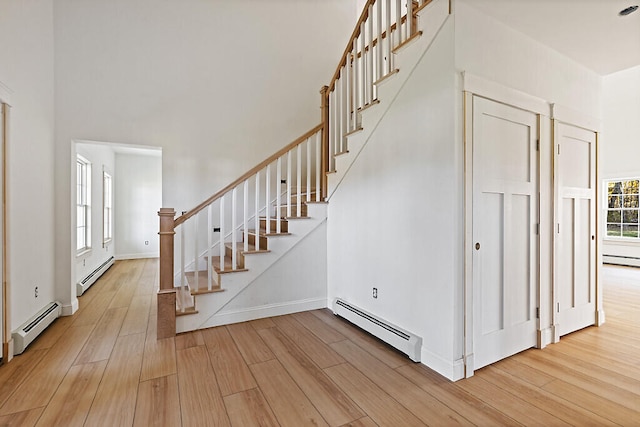 stairway with baseboard heating and hardwood / wood-style floors