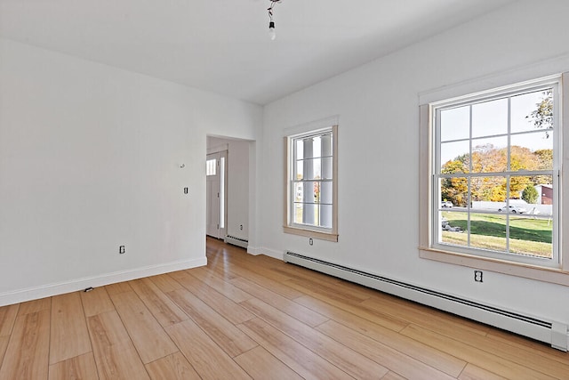 empty room with baseboard heating and light wood-type flooring