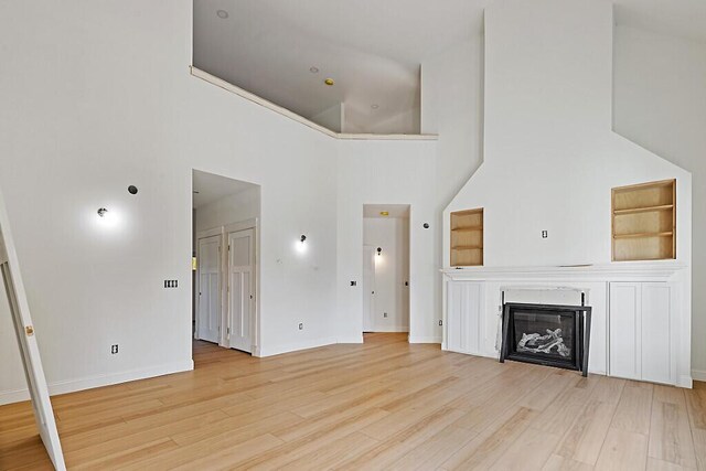 LOT1 Honey Hill Ests W, Hampden, ME 04444 - unfurnished living room with light wood-style floors, a towering ceiling, and a glass covered fireplace