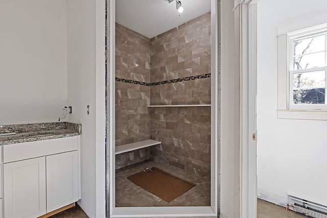 bathroom featuring baseboard heating, vanity, and a tile shower