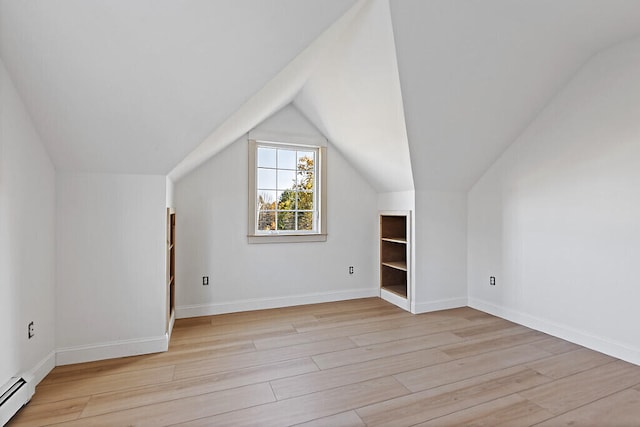 additional living space featuring a baseboard radiator, light hardwood / wood-style flooring, and lofted ceiling