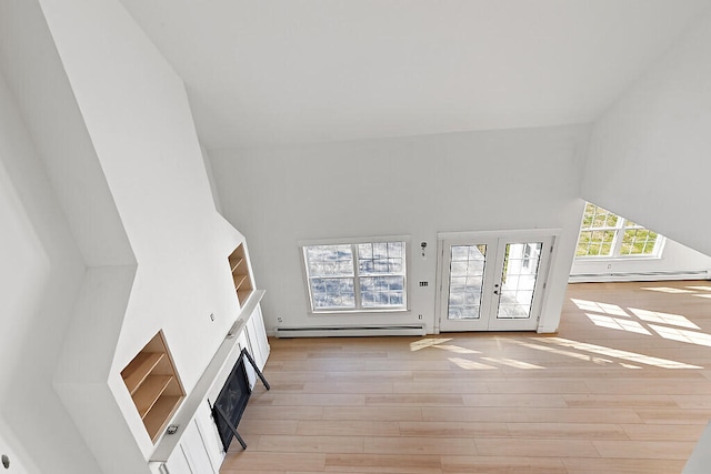 unfurnished living room with french doors, a baseboard heating unit, high vaulted ceiling, and light wood-type flooring