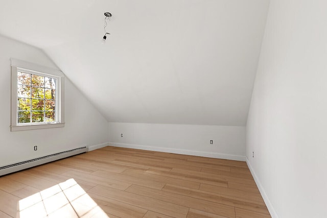 additional living space with light hardwood / wood-style floors, vaulted ceiling, and baseboard heating