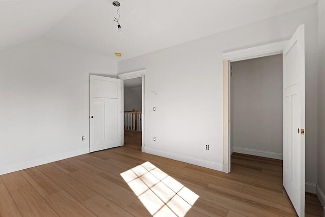 unfurnished bedroom with light hardwood / wood-style flooring and lofted ceiling