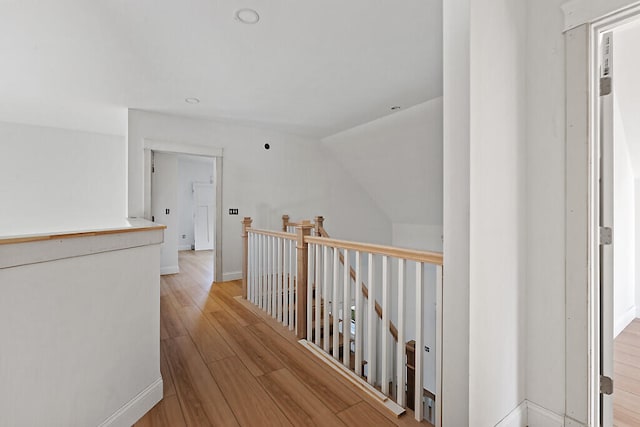 corridor with vaulted ceiling and light wood-type flooring