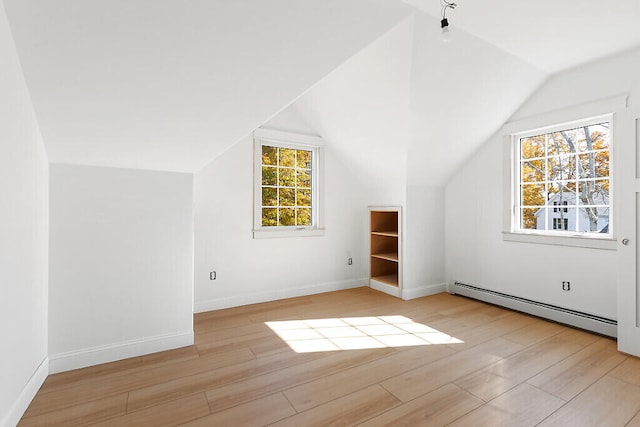 additional living space featuring a wealth of natural light, light hardwood / wood-style flooring, and baseboard heating